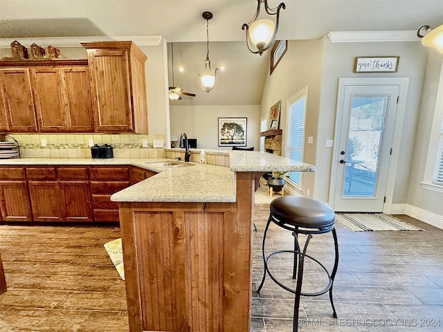 kitchen with sink, a breakfast bar area, tasteful backsplash, wood-type flooring, and decorative light fixtures