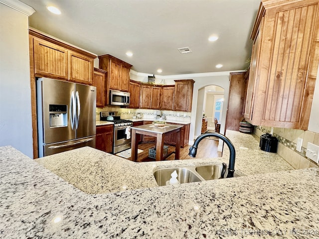 kitchen with light stone counters, sink, tasteful backsplash, and stainless steel appliances