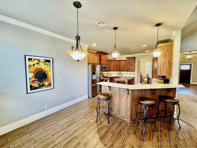 kitchen featuring decorative light fixtures, appliances with stainless steel finishes, a kitchen breakfast bar, kitchen peninsula, and hardwood / wood-style floors