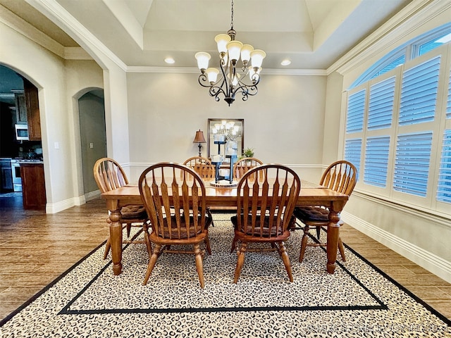 dining area featuring a raised ceiling, crown molding, hardwood / wood-style floors, and a chandelier