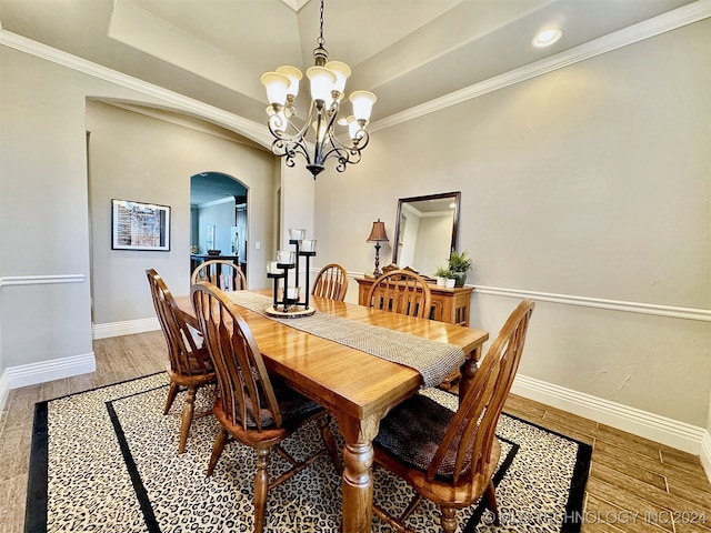 dining space featuring wood-type flooring, crown molding, a chandelier, and a tray ceiling