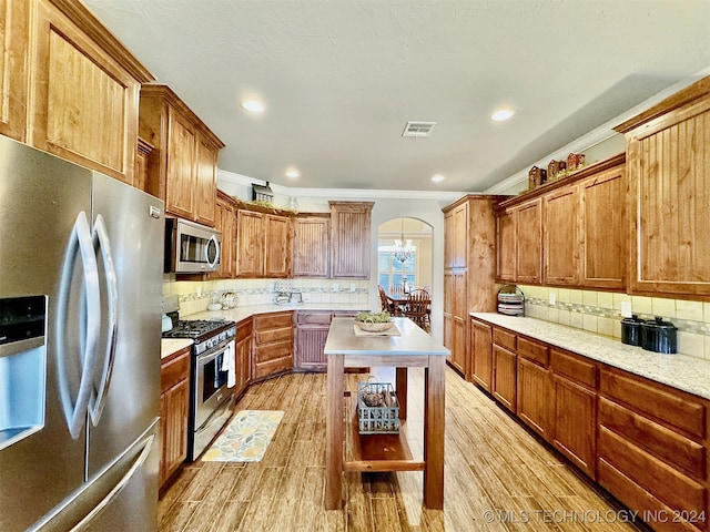 kitchen featuring tasteful backsplash, decorative light fixtures, stainless steel appliances, and light wood-type flooring