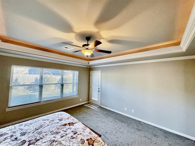 unfurnished bedroom featuring crown molding, a tray ceiling, ceiling fan, and dark colored carpet