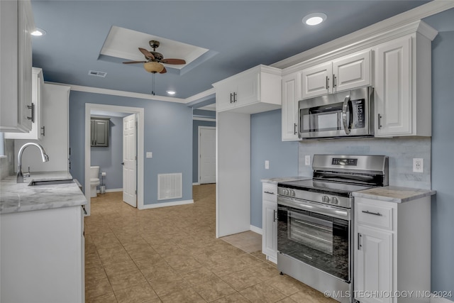 kitchen with ornamental molding, stainless steel appliances, sink, white cabinets, and ceiling fan