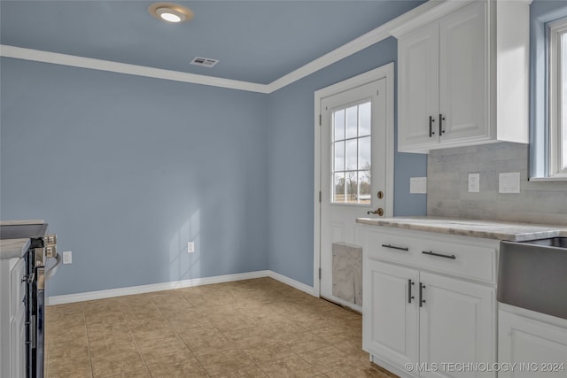 kitchen with tasteful backsplash, white cabinetry, light tile patterned floors, and crown molding