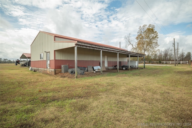 view of side of property featuring an outbuilding, central AC, and a yard