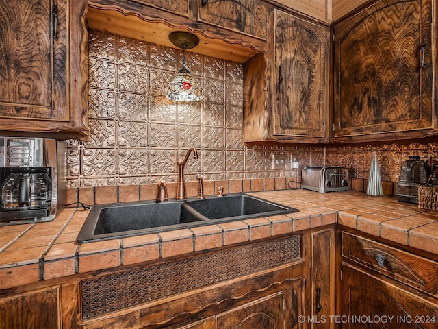 kitchen with tasteful backsplash, a sink, tile counters, and dark brown cabinetry