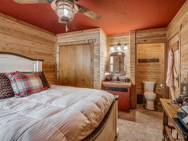 bedroom featuring light carpet, wood walls, a textured ceiling, and a ceiling fan