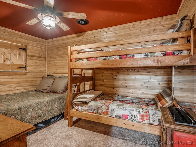 carpeted bedroom with wood walls and ceiling fan