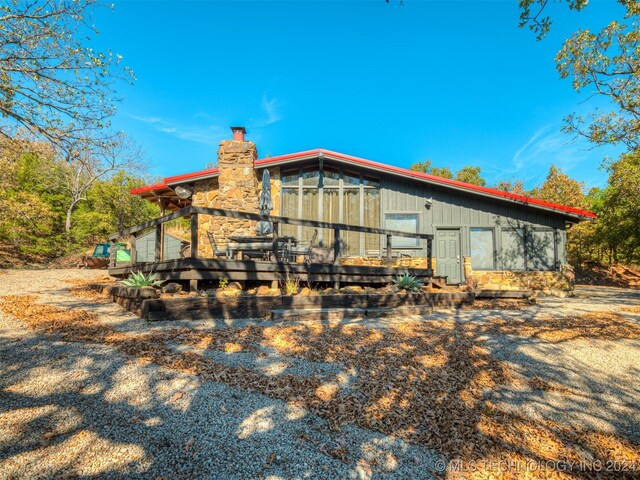 back of house with a chimney and a wooden deck