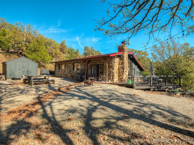 rear view of property with a storage shed, a patio area, and a deck