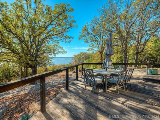 wooden terrace featuring outdoor dining area and a water view