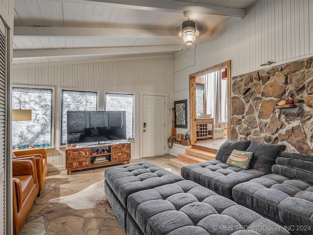 living room featuring lofted ceiling with beams, wooden walls, ceiling fan, and plenty of natural light