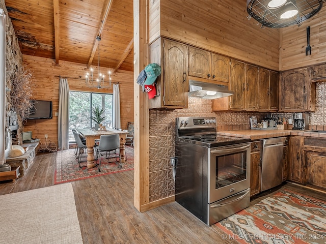 kitchen featuring appliances with stainless steel finishes, beam ceiling, wood walls, hardwood / wood-style floors, and a high ceiling