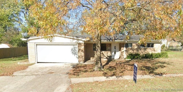 single story home with a garage, concrete driveway, brick siding, and fence