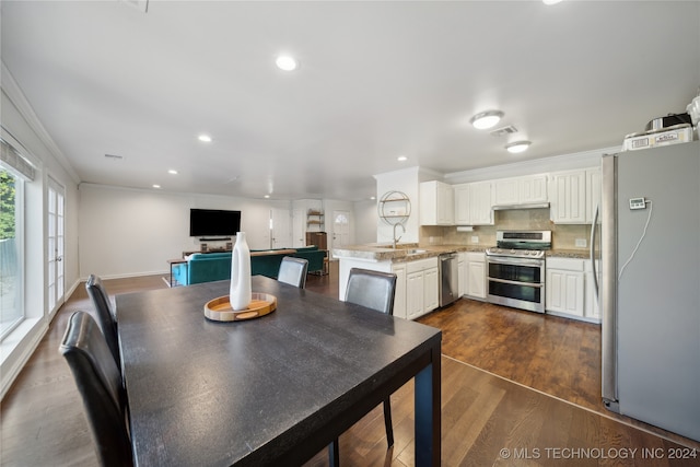 dining room with dark wood-type flooring, sink, and ornamental molding