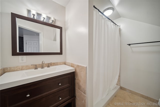 bathroom featuring walk in shower, tile patterned flooring, lofted ceiling, and vanity