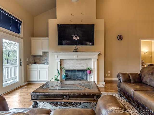 living room with high vaulted ceiling, light hardwood / wood-style floors, and a fireplace