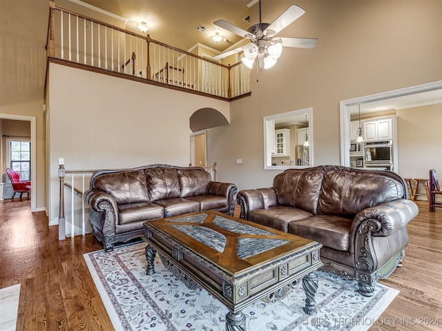 living room with hardwood / wood-style floors, ceiling fan, and a high ceiling