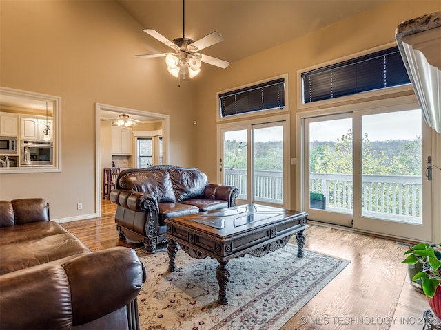 living room featuring light hardwood / wood-style flooring, ceiling fan, and a high ceiling