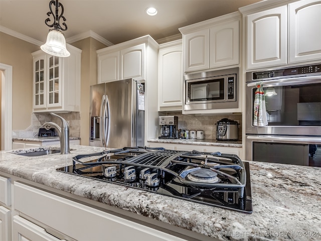 kitchen with white cabinetry, sink, appliances with stainless steel finishes, pendant lighting, and decorative backsplash