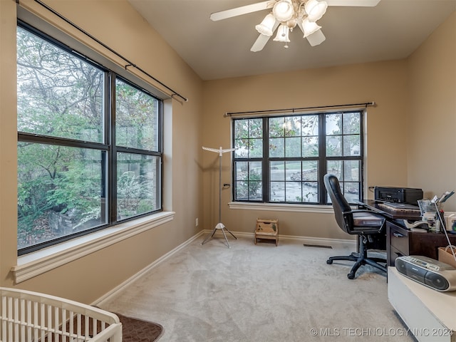 carpeted home office with a wealth of natural light and ceiling fan