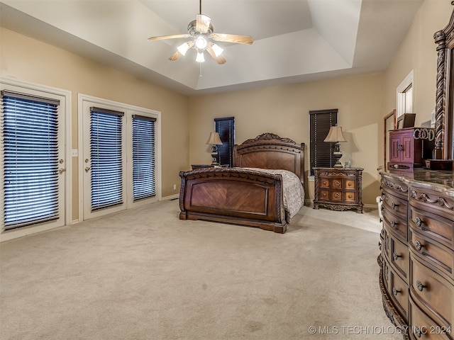 bedroom featuring ceiling fan, light carpet, and a tray ceiling