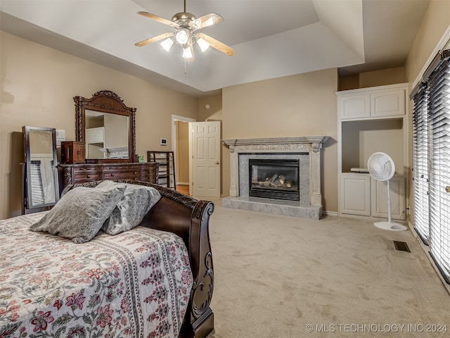 bedroom with a premium fireplace, a tray ceiling, ceiling fan, and carpet floors