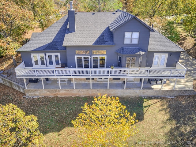 rear view of house with french doors, a lawn, and a deck