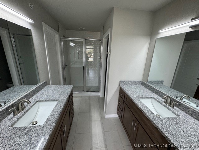 bathroom with tile patterned flooring, vanity, and a shower with door