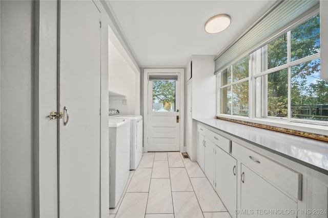 laundry room featuring cabinets, light tile patterned flooring, and washer and dryer