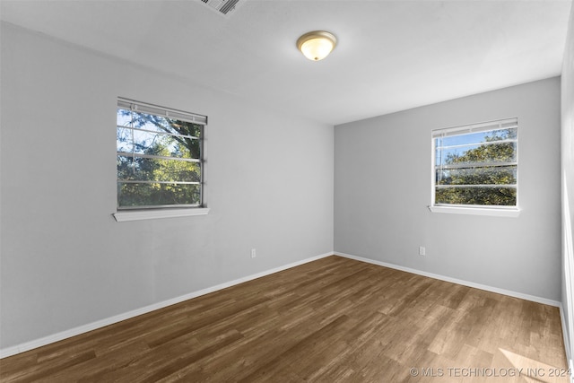 empty room with a wealth of natural light and hardwood / wood-style flooring