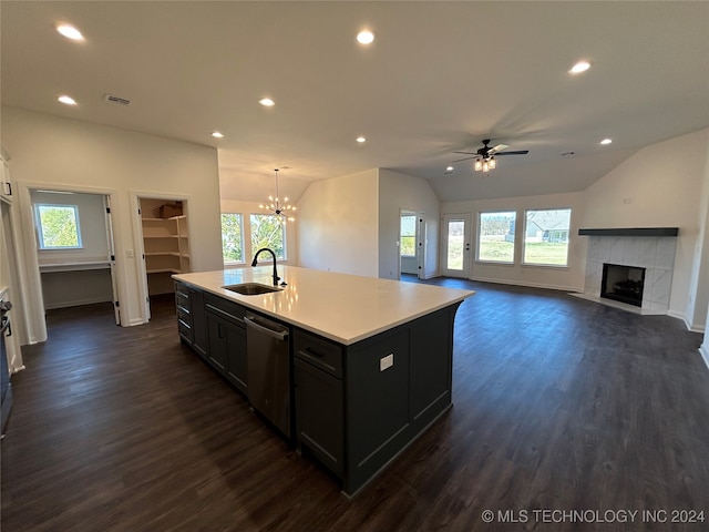 kitchen with lofted ceiling, sink, an island with sink, stainless steel dishwasher, and a fireplace