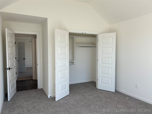 unfurnished bedroom with carpet flooring, a closet, and vaulted ceiling