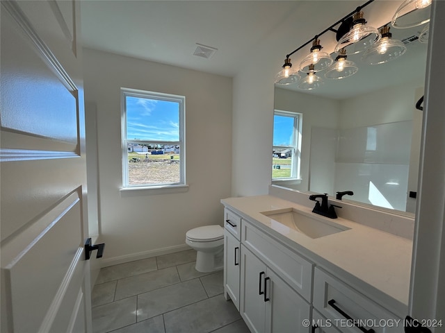 bathroom featuring tile patterned flooring, vanity, a healthy amount of sunlight, and toilet