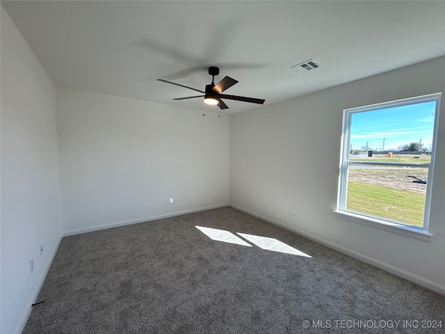 spare room featuring dark colored carpet and ceiling fan