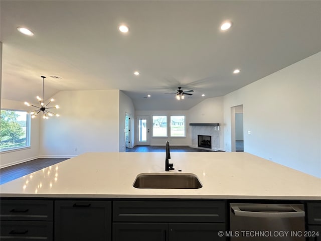 kitchen with a center island with sink, sink, a fireplace, vaulted ceiling, and dishwasher