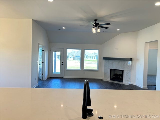 unfurnished living room featuring a tiled fireplace, dark hardwood / wood-style floors, ceiling fan, and vaulted ceiling