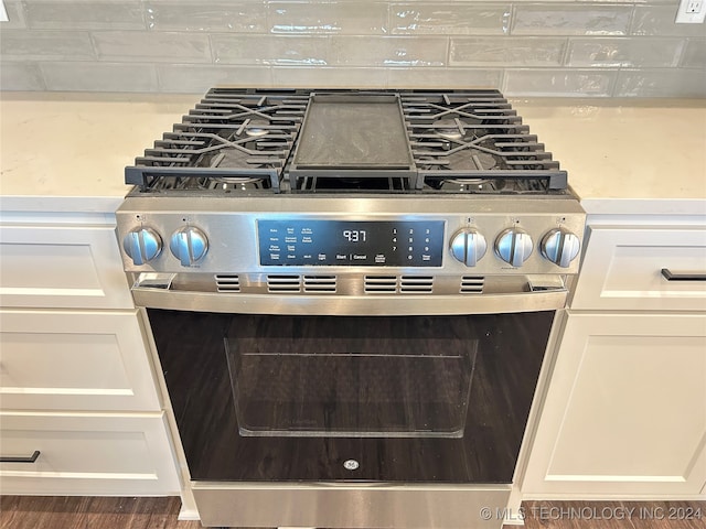 interior details featuring white cabinetry, high end stainless steel range oven, and dark hardwood / wood-style floors