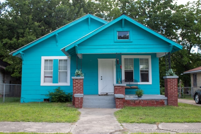 bungalow-style home with a front yard and covered porch