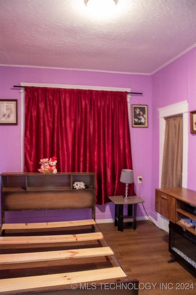 bedroom with hardwood / wood-style floors, a textured ceiling, and crown molding