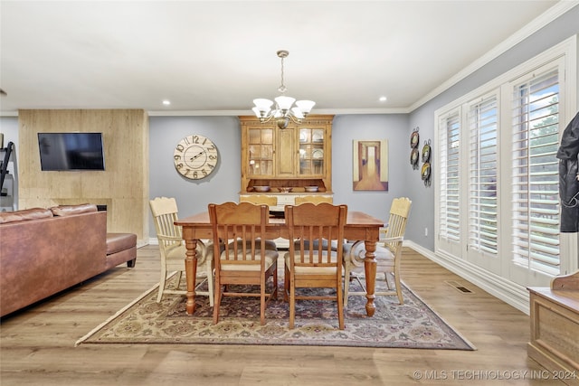 dining room featuring ornamental molding, an inviting chandelier, and light hardwood / wood-style floors