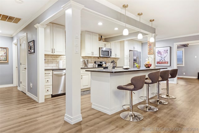 kitchen with crown molding, a kitchen island, white cabinetry, appliances with stainless steel finishes, and light hardwood / wood-style floors