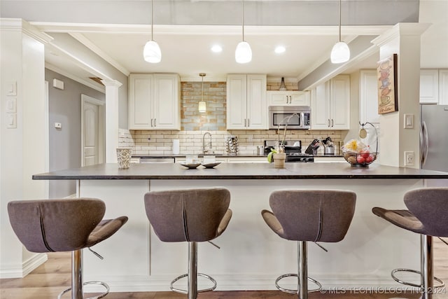 kitchen with stainless steel appliances, hanging light fixtures, a breakfast bar, and light hardwood / wood-style flooring