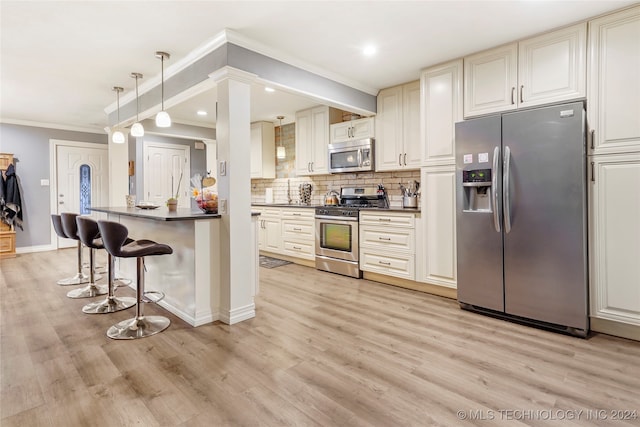 kitchen featuring crown molding, light wood-type flooring, appliances with stainless steel finishes, pendant lighting, and a kitchen breakfast bar