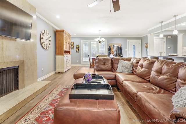 living room featuring light wood-type flooring, ornamental molding, and ceiling fan with notable chandelier