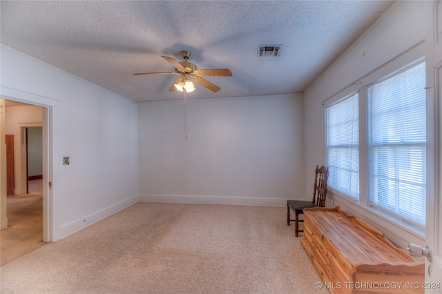 spare room with ceiling fan, light colored carpet, and a textured ceiling