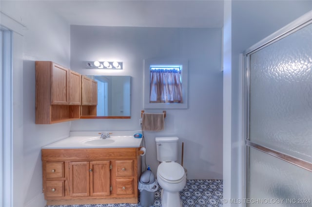 bathroom with tile patterned flooring, vanity, toilet, and a shower with door