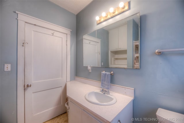 bathroom featuring vanity, a textured ceiling, and toilet