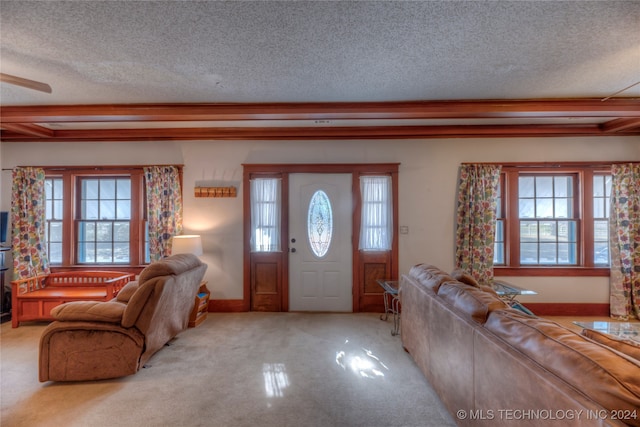 carpeted entryway featuring a wealth of natural light, a textured ceiling, and ornamental molding